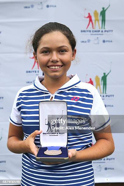 Overall champion and first place driving and putting winner Alexa Pano of the age 10-11 girls category holds her award during the regional round of...