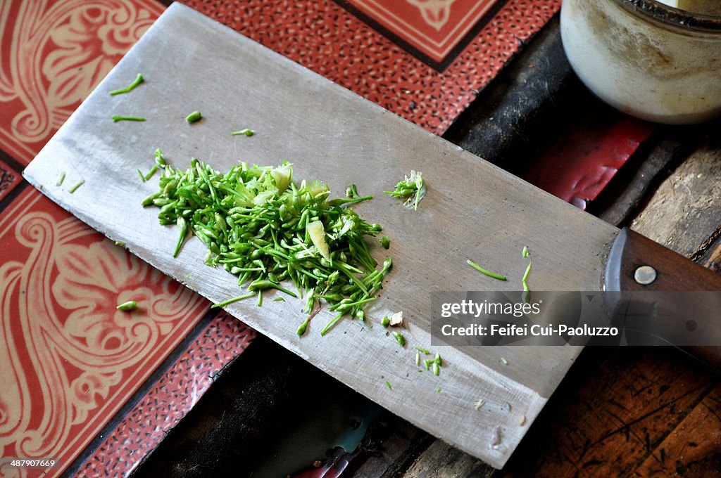 Close-up of chopped fresh herbs on a Chinese kitchen knife, at Baitang village, Shanxi Province, China