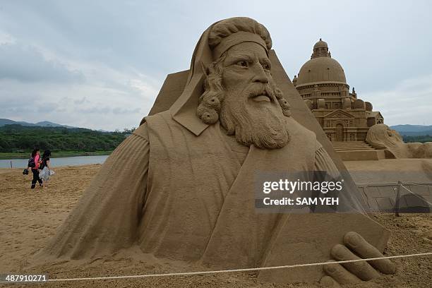 Visitors walk past a sand sculpture named "Marco Polo" during the Sand Sculpture Festival 2014 in Fulong, northern New Taipei City on May 3, 2014....