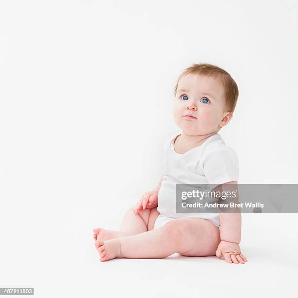 seated baby girl looking upwards - baby on white stock-fotos und bilder