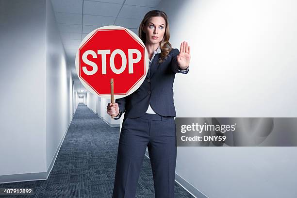 geschäftsfrau holding bis stoppschild in büro-korridor - stop einzelwort stock-fotos und bilder