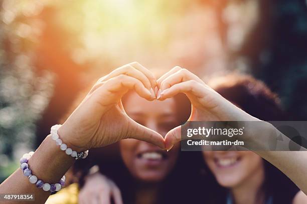 girls making heart with hands - bokeh love stock pictures, royalty-free photos & images