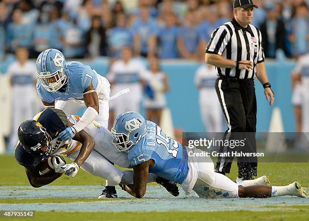 Mike Hughes and Donnie Miles of the North Carolina Tar Heels tackle Denzel Keyes of the North Carolina A&T Aggies during a game at Kenan Stadium on...