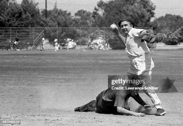 View of American gangster Mickey Cohen prepares to throw the ball from second base during a softball game on a lot across from the Twentieth Century...