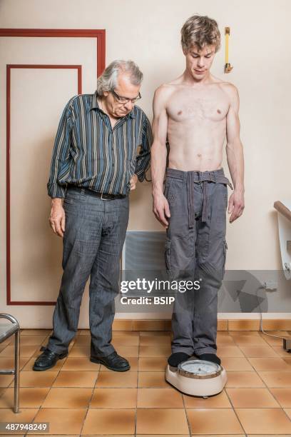 Man being weighed, doctor's surgery, France.