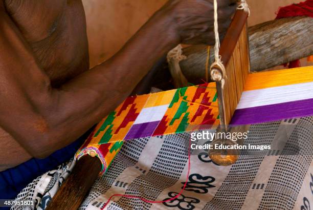 An elderly man weaves traditional kente cloth in the weaving craft village of Adanwomase in the Ashanti Region of Ghana, West Africa. Kente cloth is...