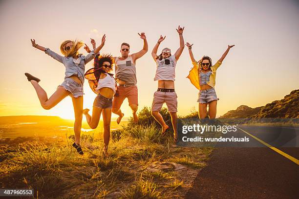 amis sauter pendant le coucher du soleil - african american women in the wind photos et images de collection