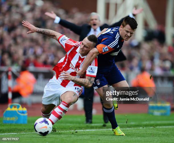 Marko Arnautovic of Stoke City is challenged by John Arne Riise of Fulham as Stoke City manager Mark Hughes appeals in the background during the...