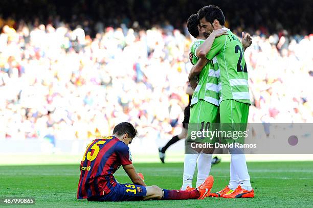 Marc Bartra of FC Barcelona sits dejected on the pitch as Jaime Gavilan and Juan Rodriguez of Getafe CF celebrate during the La Liga match between FC...