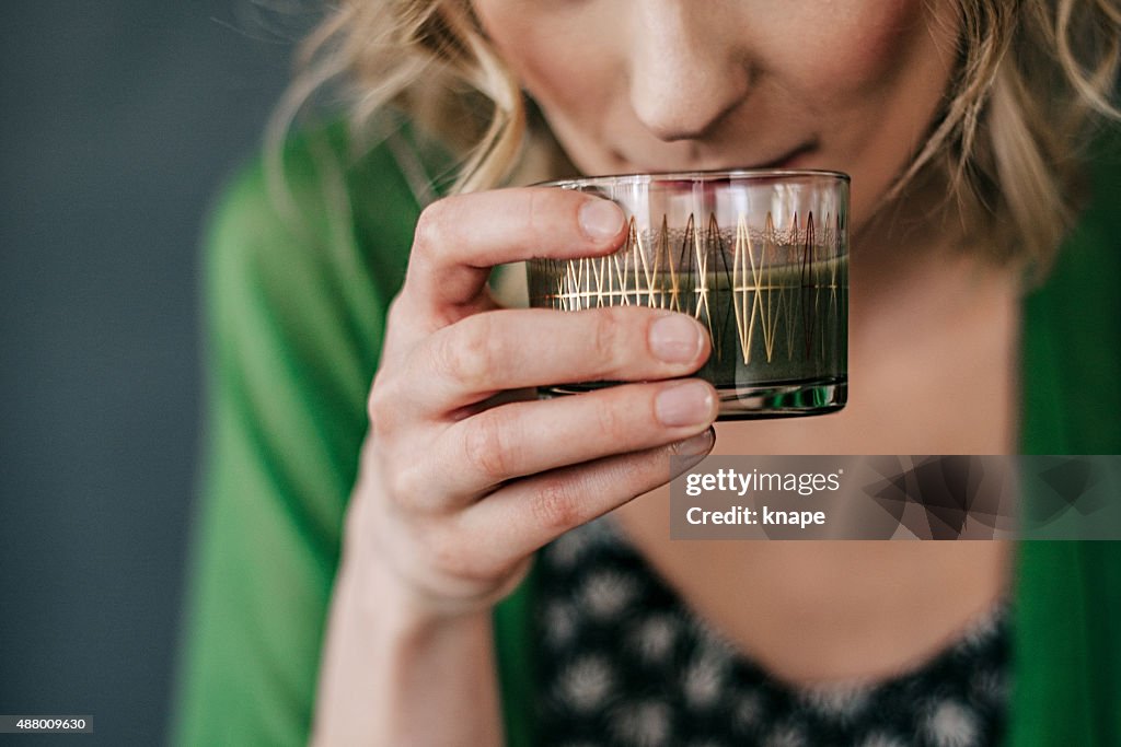 Jeune femme buvant un jus de fruits vert