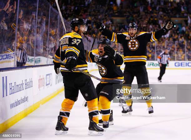 Patrice Bergeron of the Boston Bruins celebrates his tying goal in the third period with teammates Brad Marchand and Dougie Hamilton against the...