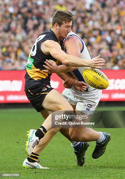 Kane Lambert of the Tigers kicks whilst being tackled by Ben Cunnington of the Kangaroos during the First AFL Elimination Final match between the...