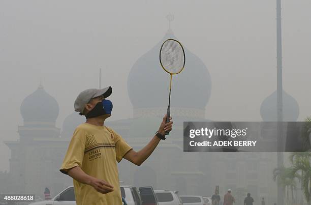 Man plays badminton while wearing a face mask in the grounds of the An-Nur Great Mosque as haze shrouds the Sumatran city of Pekanbaru, in Riau...