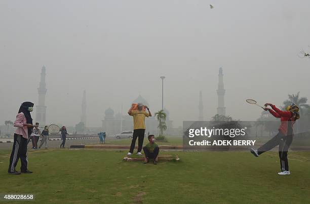 People play badminton while wearing face masks in the grounds of the An-Nur Great Mosque as haze shrouds the Sumatran city of Pekanbaru, in Riau...