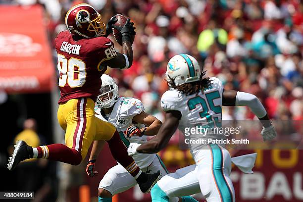Wide receiver Jamison Crowder of the Washington Redskins catches the ball while cornerback Walt Aikens of the Miami Dolphins and cornerback Brent...