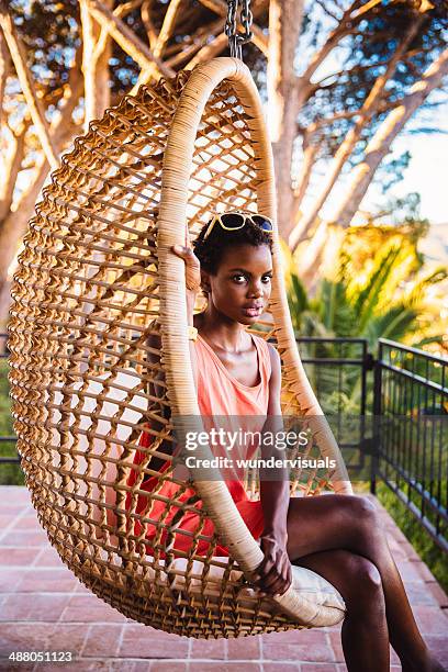 young woman sitting in a hanging chair - hanging chair stock pictures, royalty-free photos & images