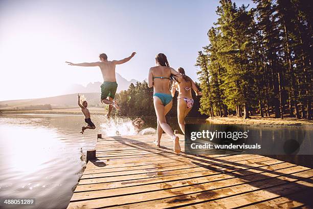 springen in das wasser aus anlegesteg - badebekleidung stock-fotos und bilder