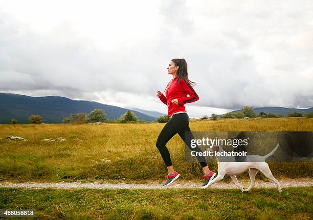 junge frau mit ihrem hund joggen - run shirt stock-fotos und bilder