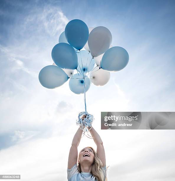 woman holding a bunch of helium balloons outdoors - balloons in sky stock pictures, royalty-free photos & images