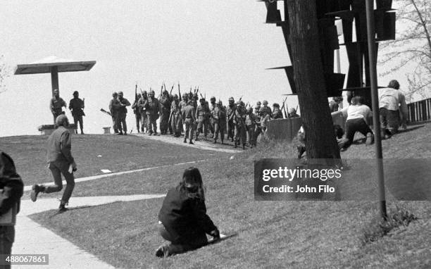 As Ohio National Guard troops march on campus, students crouch down to take cover during an anti-war demonstration at Kent State University, Kent,...