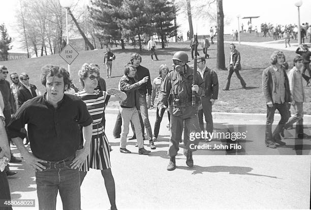 Students and protesters stand around a lone Ohio National Guard soldier, in a gas mask and with a rifle in his hands, during an anti-war...