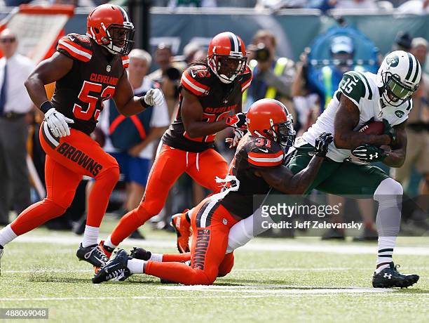 Brandon Marshall of the New York Jets runs from Donte Whitner of the Cleveland Browns after recovering the football against the Cleveland Browns...