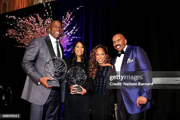 Earvin "Magic" Johnson and Cookie Johnson accept awards from Steve and Marjorie Harvey on stage at the 2014 Steve & Marjorie Harvey Foundation Gala...