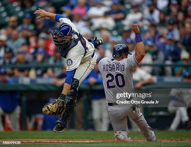 Wilin Rosario of the Colorado Rockies scores from third against catcher Steve Baron of the Seattle Mariners in the fourth inning at Safeco Field on...