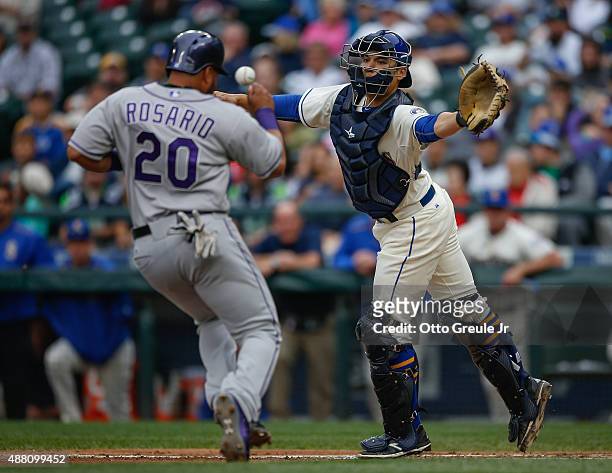 Wilin Rosario of the Colorado Rockies scores from third against catcher Steve Baron of the Seattle Mariners in the fourth inning at Safeco Field on...