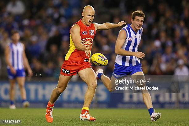 Gary Ablett of the Suns kicks the ball for a goal ahead of Shaun Atley of the Kangaroos during the round seven AFL match between the North Melbourne...