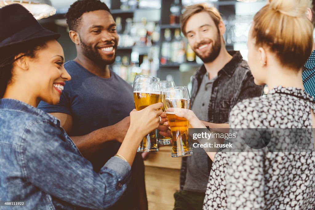 Friends toasting with beer in a pub