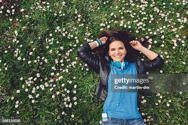 smiling teenage girl lying down in the grass - girl lying down stock pictures, royalty-free photos & images