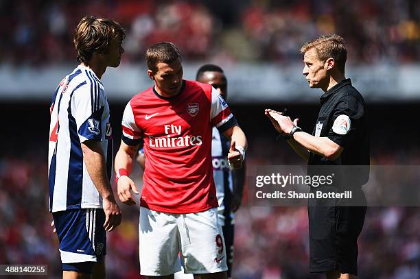 Match referee Mike Jones talks to Diego Lugano of West Bromwich Albion and Lukas Podolski of Arsenal during the Barclays Premier League match between...