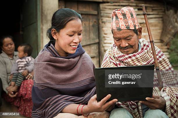 rural asian young woman showing laptop to a senior man. - nepal stock pictures, royalty-free photos & images