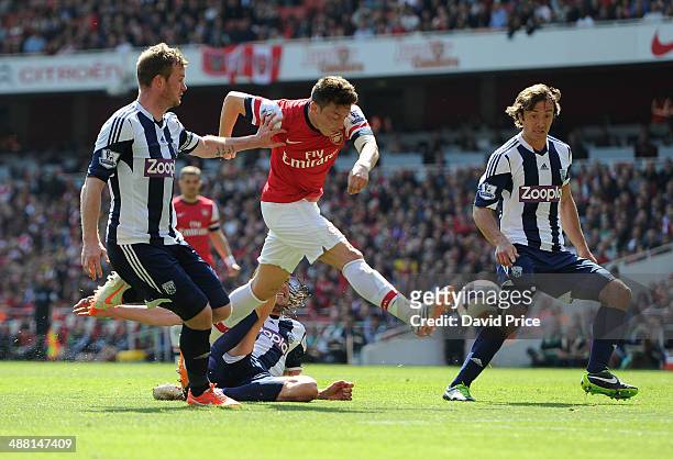 Mesut Oezil of Arsenal under pressure from Chris Brunt and Diego Lugano of West Brom during the match between Arsenal and West Bromwich Albion in the...