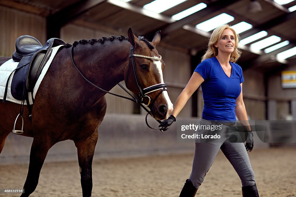 Woman walking with horse indoors