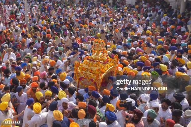 Indian Sikh devotees carry the Palki Sahib with the Guru Granth Sahib, the central religious text of Sikhism during a religious procession from...