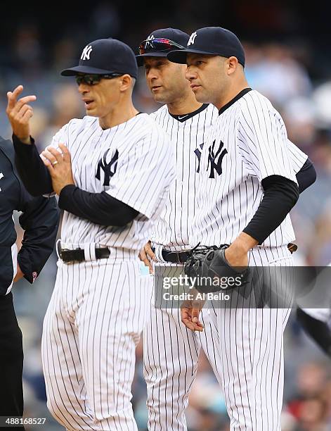 Manager Joe Girardi of the New York Yankees calls a trainer to look at Alfredo Aceves who appears to have an injury to his leg in the fifth inning of...