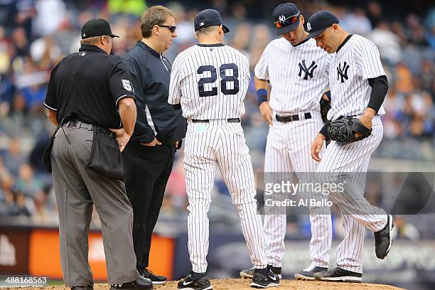 Manager Joe Girardi of the New York Yankees and Derek Jeter look at Alfredo Aceves who appears to have an injury to his leg in the fifth inning of...