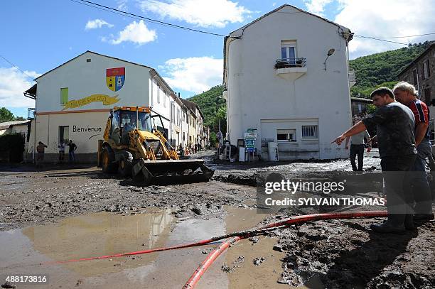 Municipal workers clean the mud-covered central square of the village of Molieres-sur-Ceze after torrential downpours damaged roads and washed away...