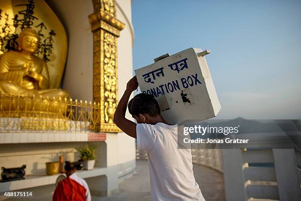 Young man carries a donation box up to the monastery that is located in Pokhara Valley.