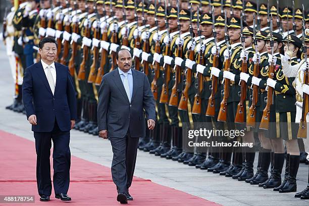 Chinese President Xi Jinping accompanies Mauritania's President Mohamed Ould Abdel Aziz to view an honour guard during a welcoming ceremony outside...