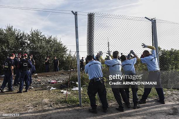 Inmates of the "Csillag" jail of Szeged fix an iron fence at the Hungarian-Serbian border near the town of Horgos on September 14, 2015 as Hungarian...