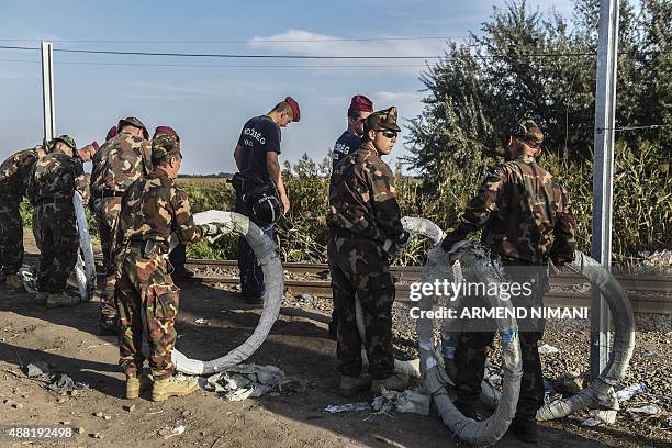 Hungarian military personnel fix an iron fence at the Hungarian-Serbian border near the town of Horgos on September 14, 2015 as Hungarian police...