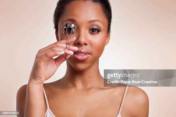 young lady curling her eyelashes with a curler - eye make up stock pictures, royalty-free photos & images