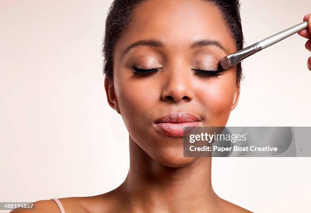 woman having eyeshadow applied on her face - eyeshadow fotografías e imágenes de stock