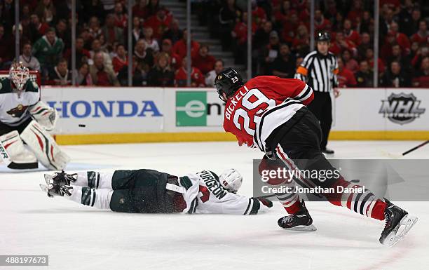Bryan Bickell of the Chicago Blackhawks shoots the puck over Jared Spurgeon of the Minnesota Wild to score a third period goal against Ilya Bryzgalov...