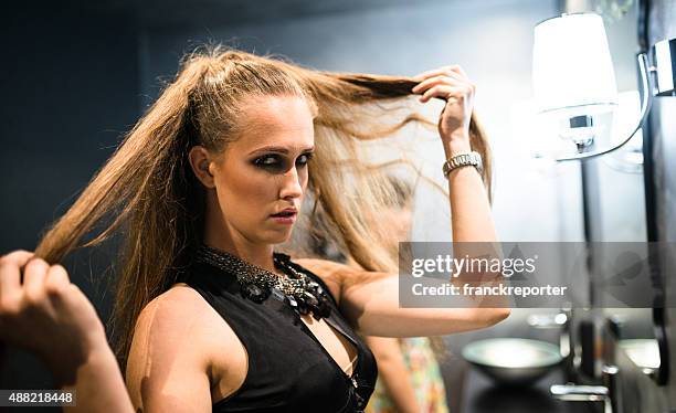 woman fixing her hair in front of the mirror - nightclub bathroom stock pictures, royalty-free photos & images