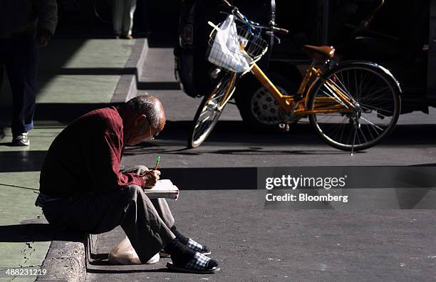 Man sits writing in a book in the Airin area of Nishinari ward in Osaka, Japan, on Friday, May 2, 2014. Osaka prefecture's economic output dropped...