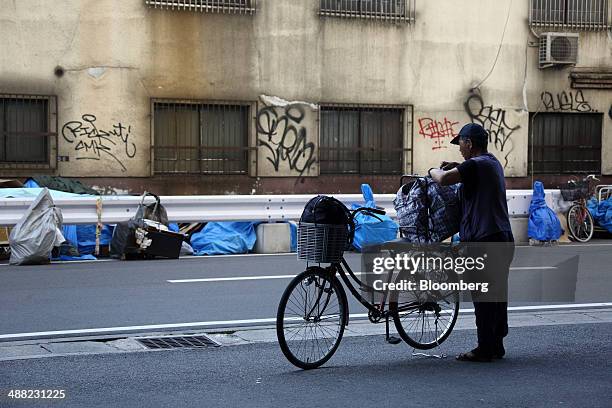 Man secures a bag on a bicycle in the Airin area of Nishinari ward in Osaka, Japan, on Friday, May 2, 2014. Osaka prefecture's economic output...